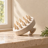 Scalp massage brush on a travertine shelf