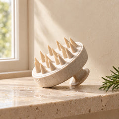 Scalp massage brush on a travertine shelf