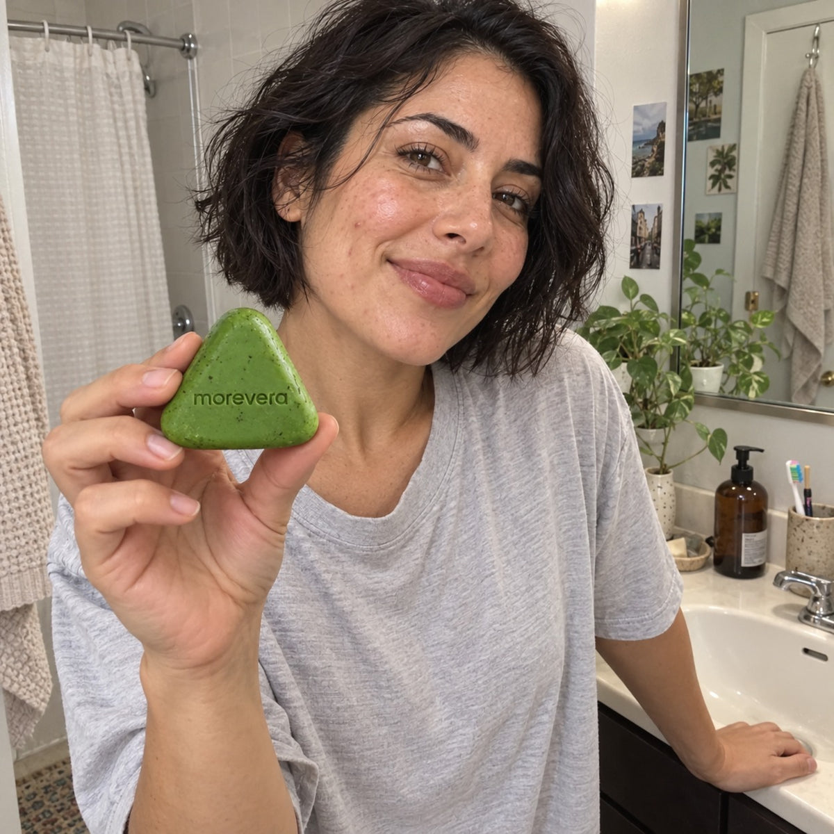 Woman with short dark hair in her bathroom holding the green Korean Scalp Reset Bar